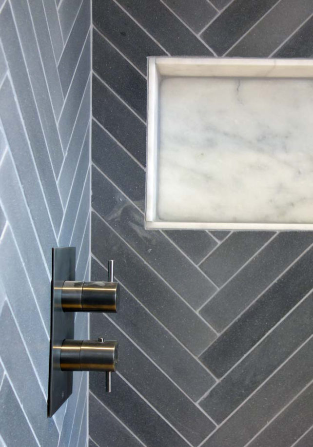 Grey bathroom tiles with brassware.